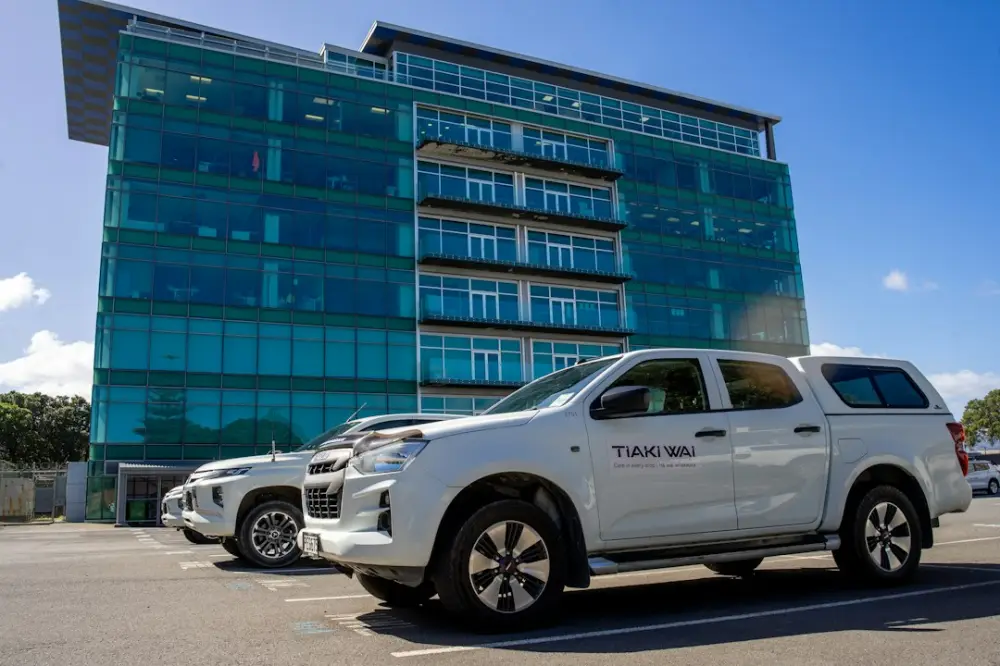 Two white pickup trucks parked in a lot before a modern glass office building, illustrating fleet funding literacy